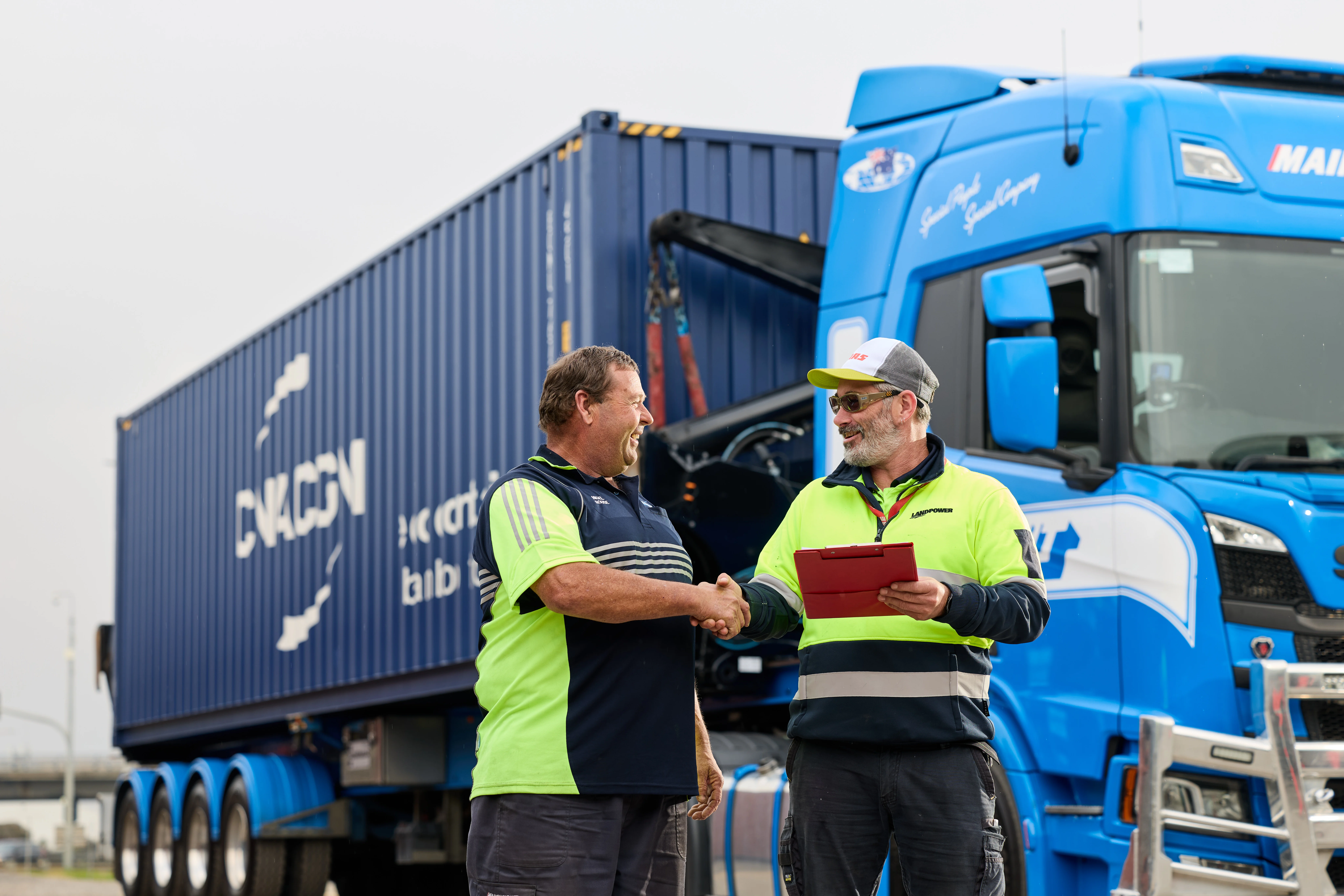 Mainfreight Team member in front of a side loader container truck